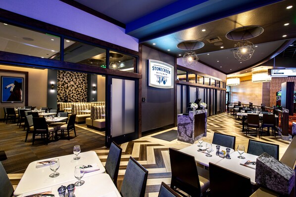 A restaurant with multiple dining areas, a sign for Stonecreek Kitchen, and a variety of seating arrangements.
