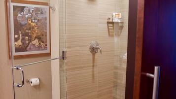 A glass-enclosed shower with a handheld showerhead, a towel rack, and a toilet paper holder on the wall.