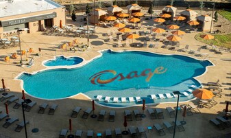 Una piscina con un gran logotipo, tumbonas, sombrillas y un bar.