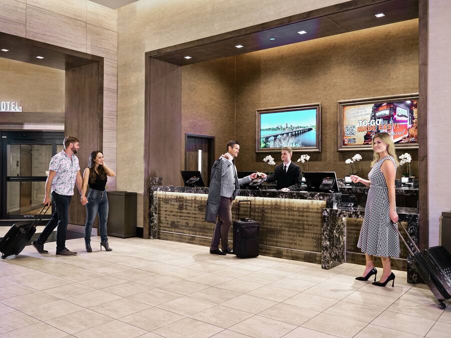 A hotel reception area with a reception desk, a television screen, and a sign indicating the hotel's location.