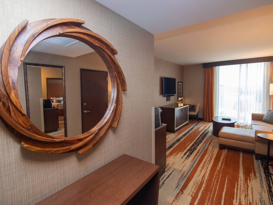 Een hotelkamer met een grote houten spiegel, een bank, een salontafel, een televisie en een vloerbedekking.