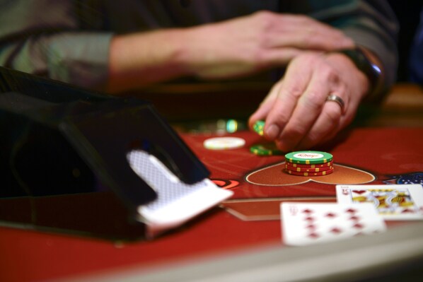 Primer plano de manos repartiendo cartas y fichas en una mesa de casino.