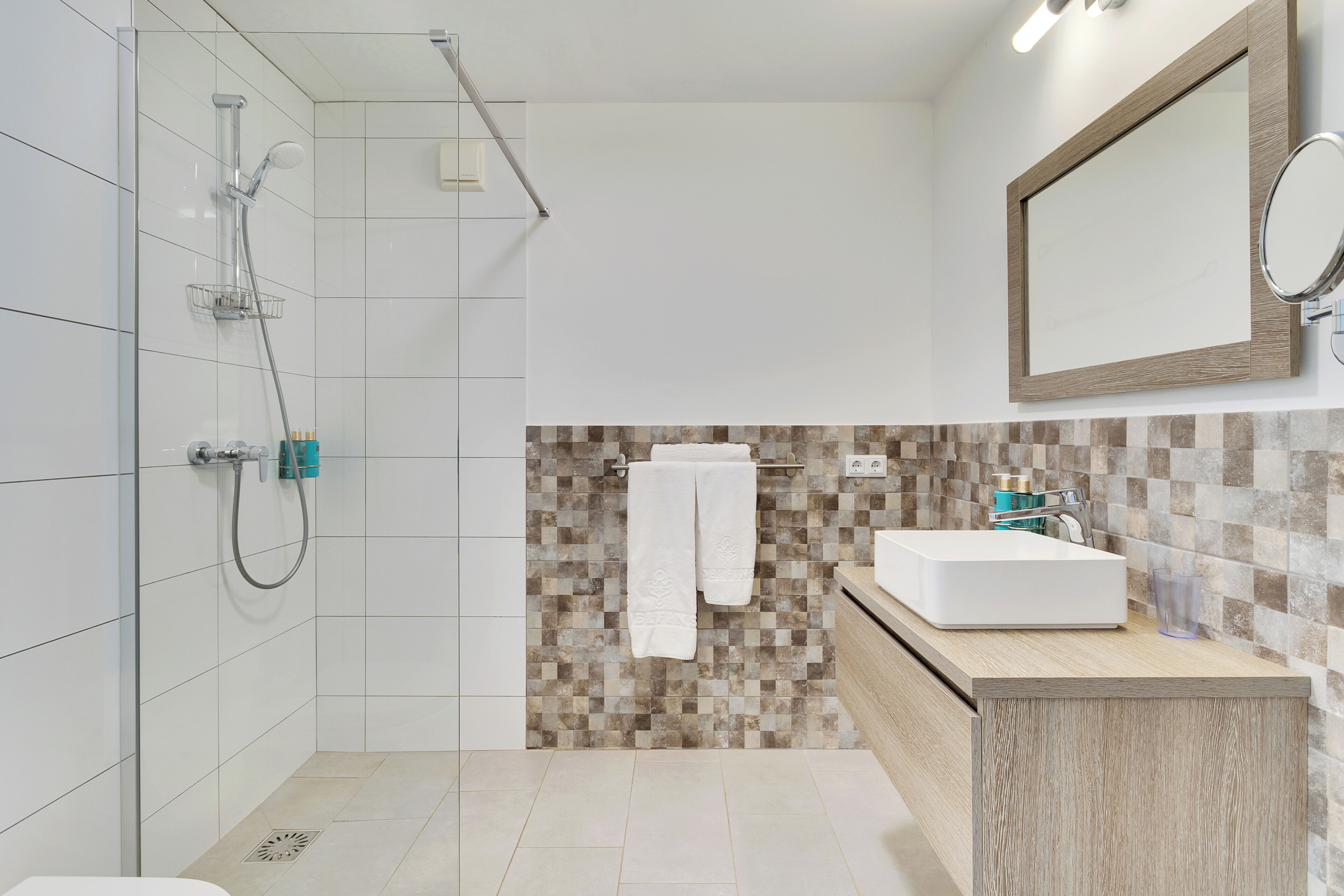 Une salle de bain moderne avec une douche, un lavabo et un miroir.