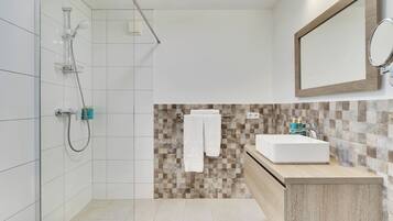 Une salle de bain moderne avec une douche, un lavabo et un miroir.