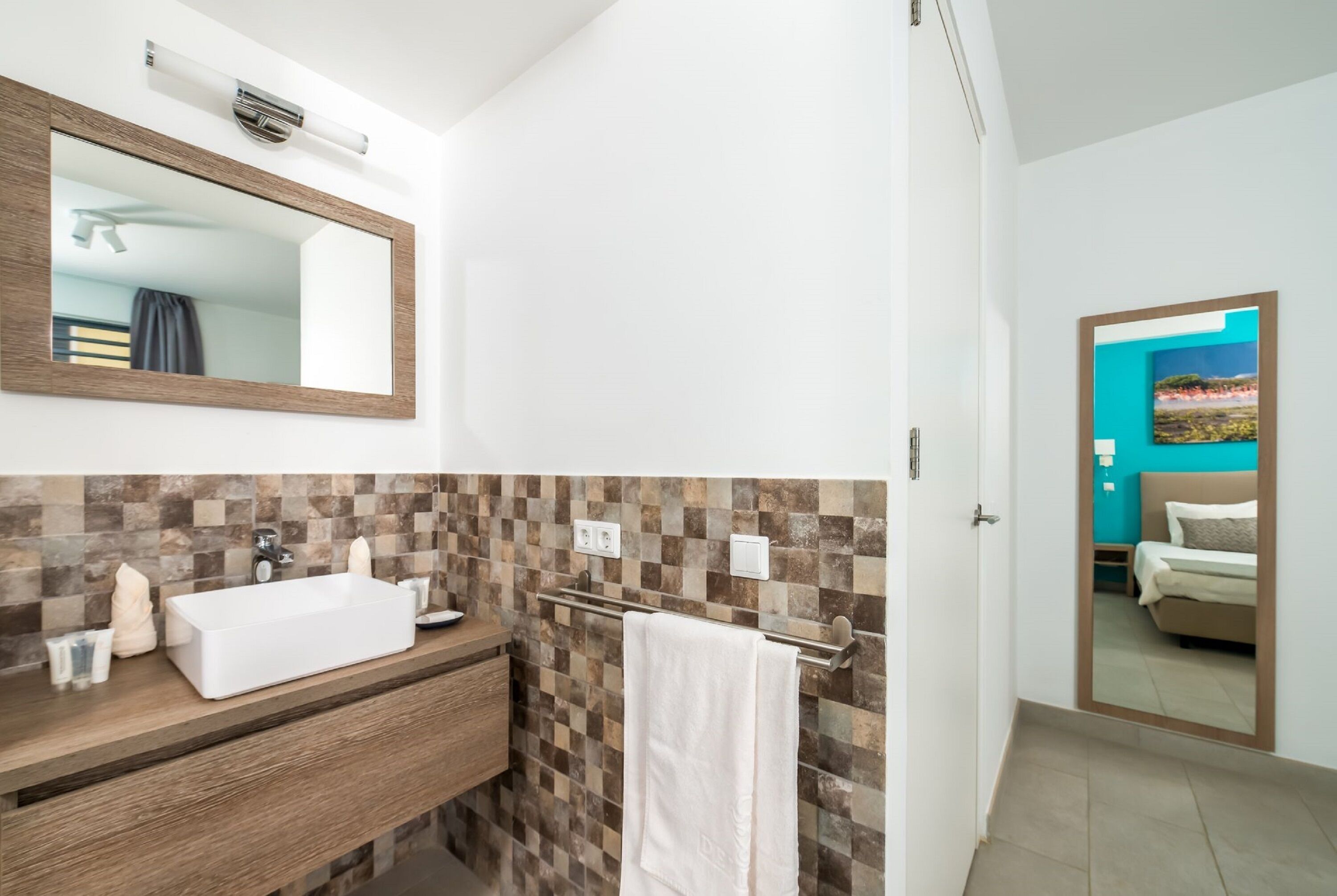 A modern bathroom with a white sink, wooden vanity, and a mirror.
