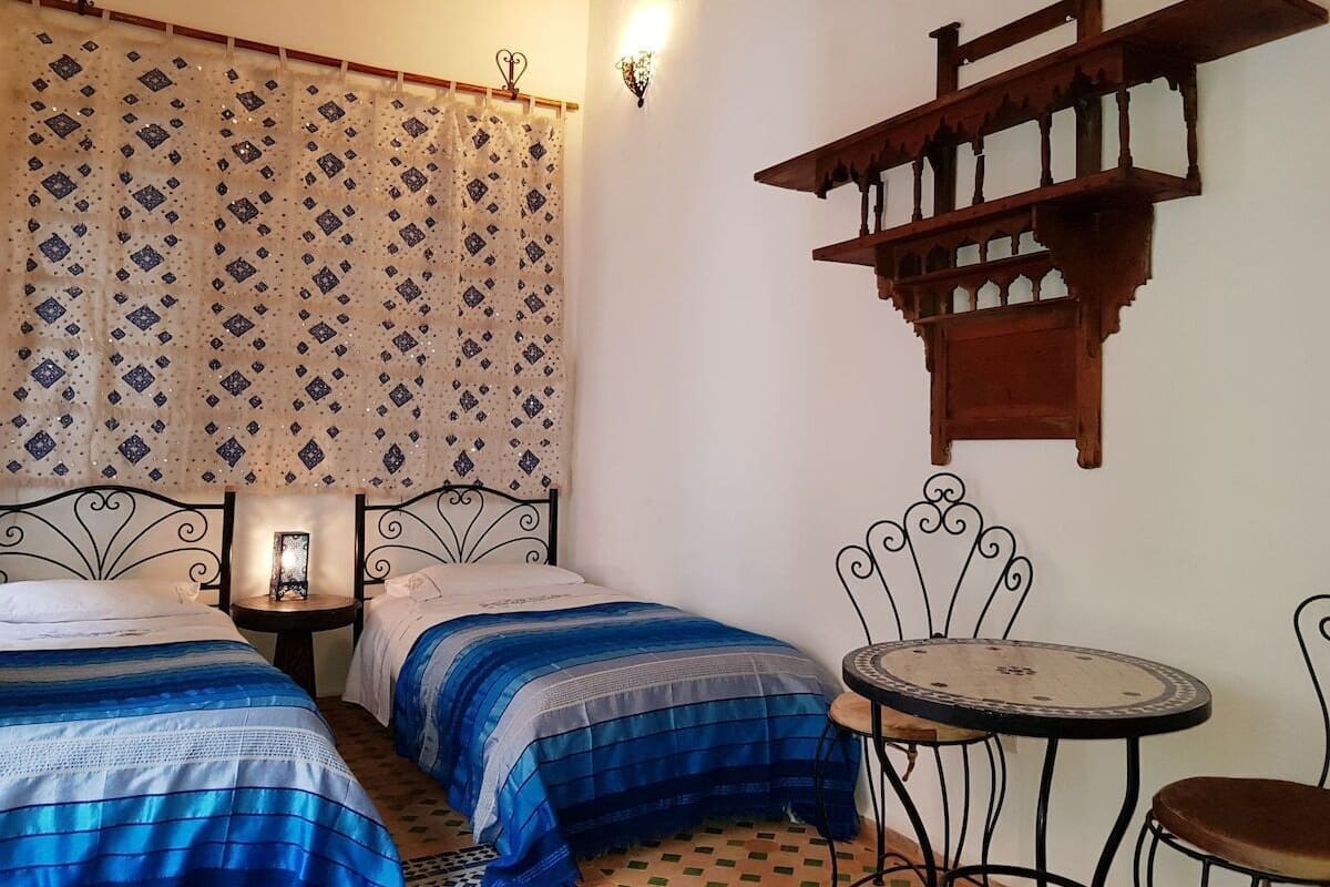 Quarto com duas camas, uma mesinha e uma cadeira.