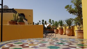 Un patio con suelo de baldosas, plantas en macetas y una escalera que conduce a un nivel superior.