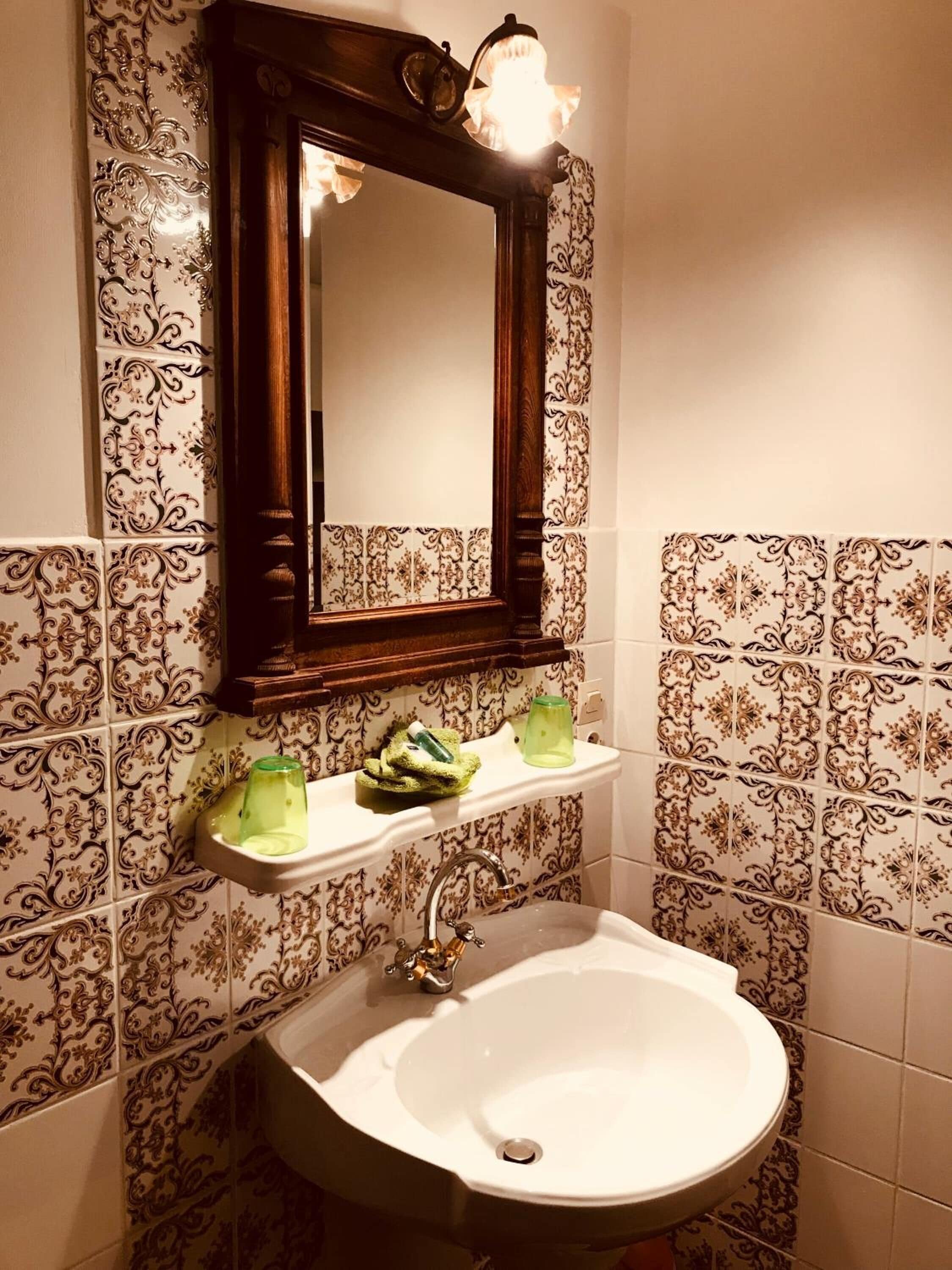 A bathroom with a white sink, a mirror, and decorative tiles.