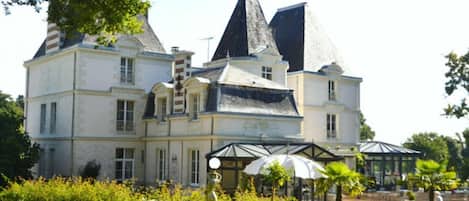 Un edificio grande e histórico con múltiples torres y un jardín bien cuidado.