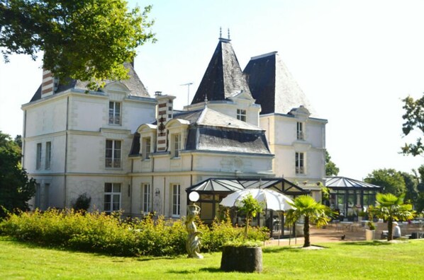 Un grand bâtiment historique doté de nombreuses tours et d’un jardin bien entretenu.