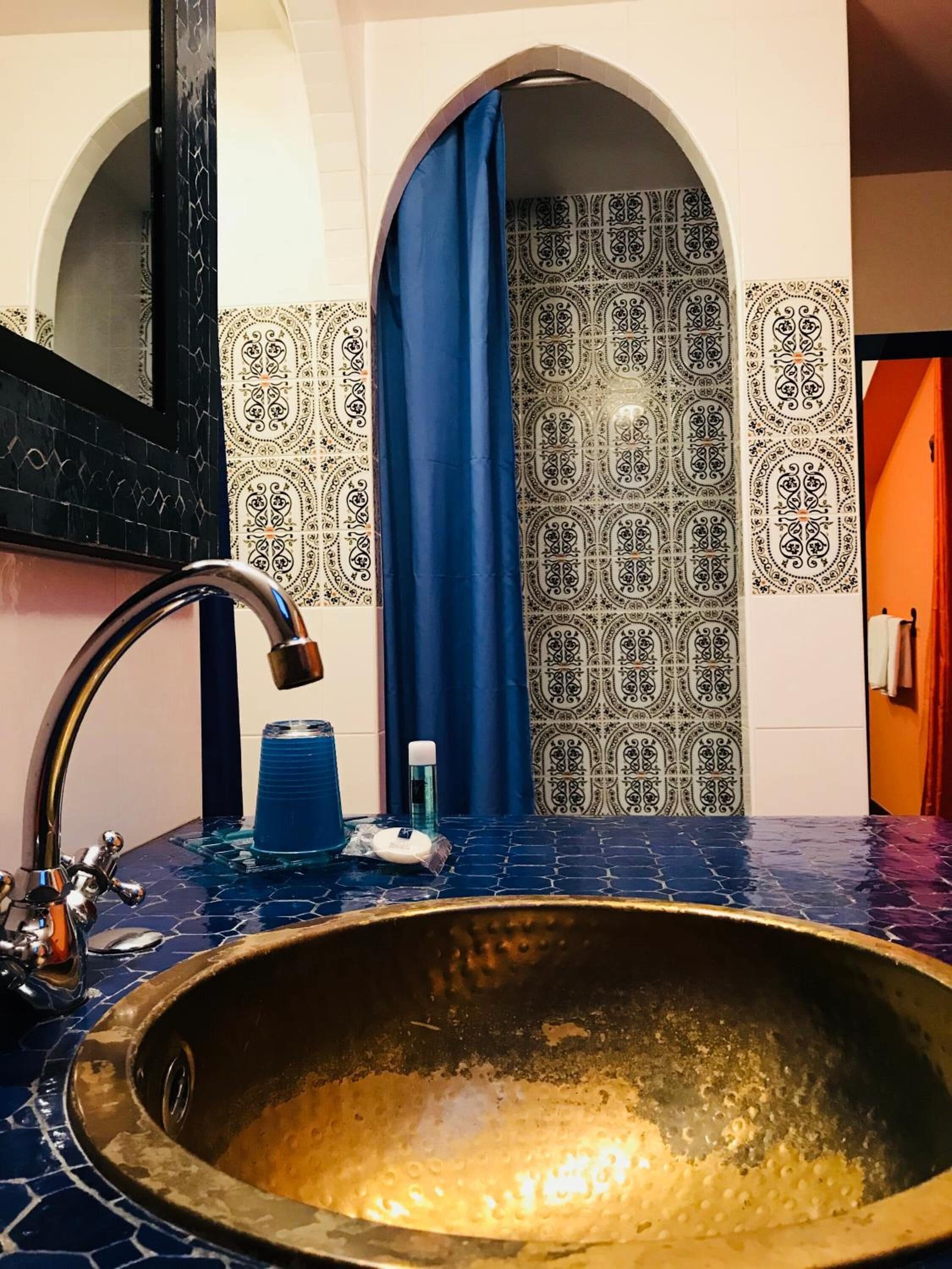 Um banheiro com uma pia grande e decorada, um espelho e azulejos estampados.