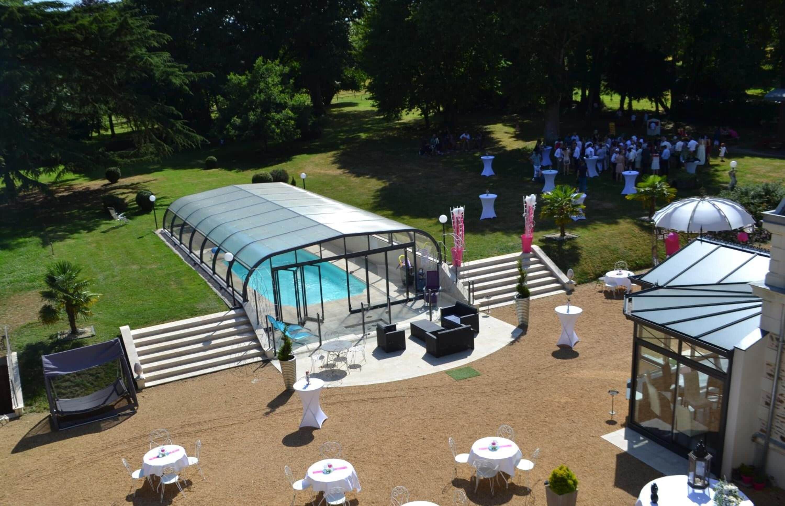 Un área de patio exterior con piscina, mobiliario cubierto y mesas.