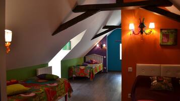 A room with two beds, a sloped ceiling, and a wall-mounted lamp.