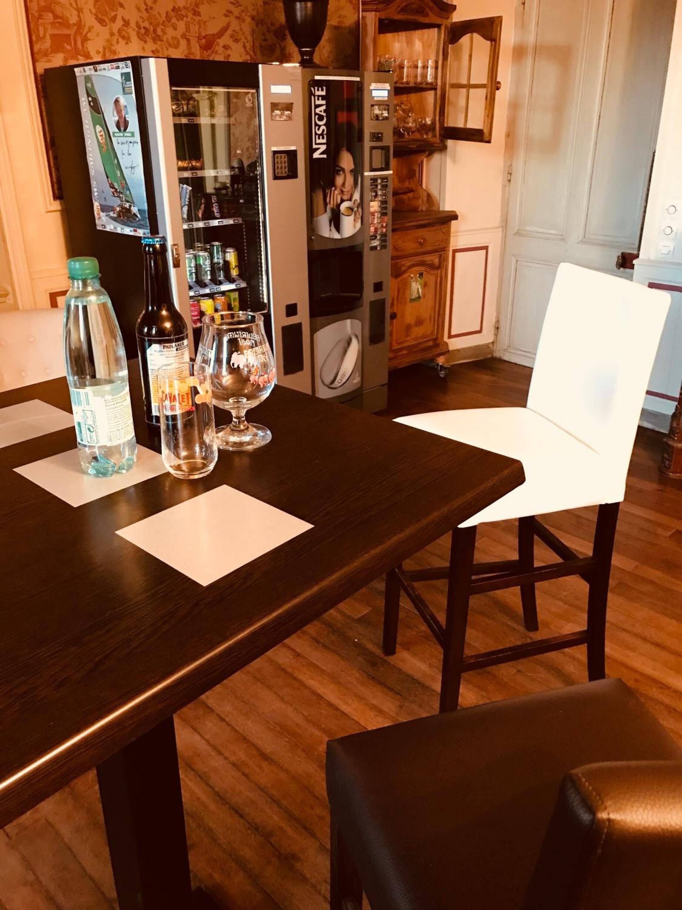 A dining area with a wooden table, two chairs, and a Nescafé coffee machine.