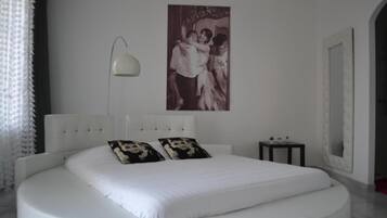 Un dormitorio moderno con cama redonda, lámpara de pared e imagen enmarcada.