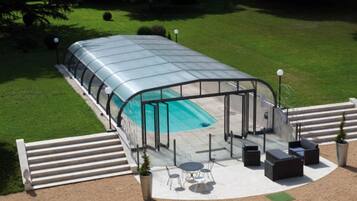 Ein überdachter Pool mit einer Terrassenanlage, inklusive Sitzgelegenheiten und einem kleinen Tisch.
