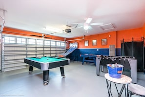 Una sala ricreativa con tavolo da biliardo, tavolo da calcio e tavolo da ping pong.
