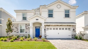 A two-story house with a blue front door, a garage, and a well-maintained lawn. - Champions Gate 1686 (Davenport)
