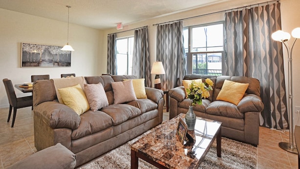 A living room with two brown leather sofas, a coffee table, and a painting on the wall.
