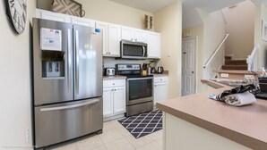 A modern kitchen with stainless steel appliances, white cabinetry, and a microwave. - Bella Vida 4550 (Kissimmee)