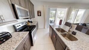 A modern kitchen with granite countertops, stainless steel appliances, and a large window offering a view of the outdoors.