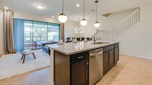 Una cucina moderna con isola centrale, elettrodomestici in acciaio inossidabile e illuminazione a sospensione.