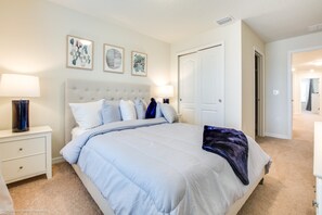 A bedroom with a large bed, a nightstand with a lamp, and a door leading to another room. - Solterra 4663 (Davenport)