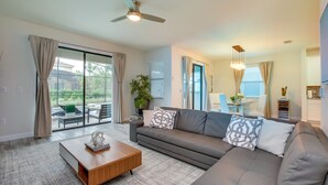 Ein modernes Wohnzimmer mit einem grauen Sofa, einem Holztisch und einem Deckenventilator.