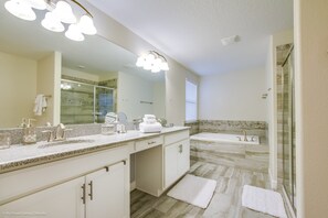 Une salle de bain moderne dotée d’un grand miroir, de deux lavabos, d’une baignoire et d’un espace douche.