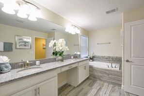 Ein Badezimmer mit großem Spiegel, Waschbecken, Badewanne und Toilette.