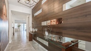 A modern reception area with a glass desk, wooden panel wall, and a view of the hallway. - Solara Resort 9031 D (Kissimmee)