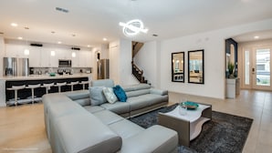 A modern living room with a grey sectional sofa, a coffee table, and a staircase leading to an upper floor.
