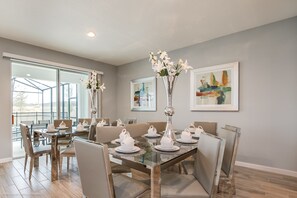 A dining area with a glass table, chairs, and white teapots. There are two vases with flowers on the table. - Sonoma Resort 2619 (Kissimmee)