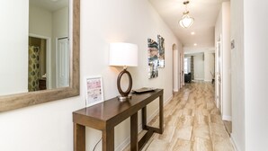 A hallway with a wooden console table, a mirror, and framed artwork. - Storey Lake 4720 (Kissimmee)