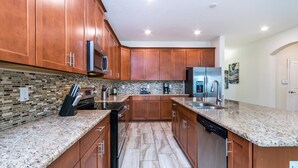 A kitchen with wooden cabinets, granite countertops, stainless steel appliances, and a tiled backsplash. - Storey Lake 4720 (Kissimmee)
