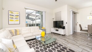 A modern living room with a white sofa, glass coffee table, and a flat-screen TV. - Storey Lake 3081 (Kissimmee)