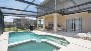 Une piscine extérieure couverte offrant une vue sur un quartier résidentiel, avec notamment une maison et une pelouse.