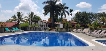 Una piscina al aire libre, sillones reclinables de piscina