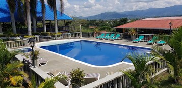 Piscina con sillas de descanso y vistas a montañas.
