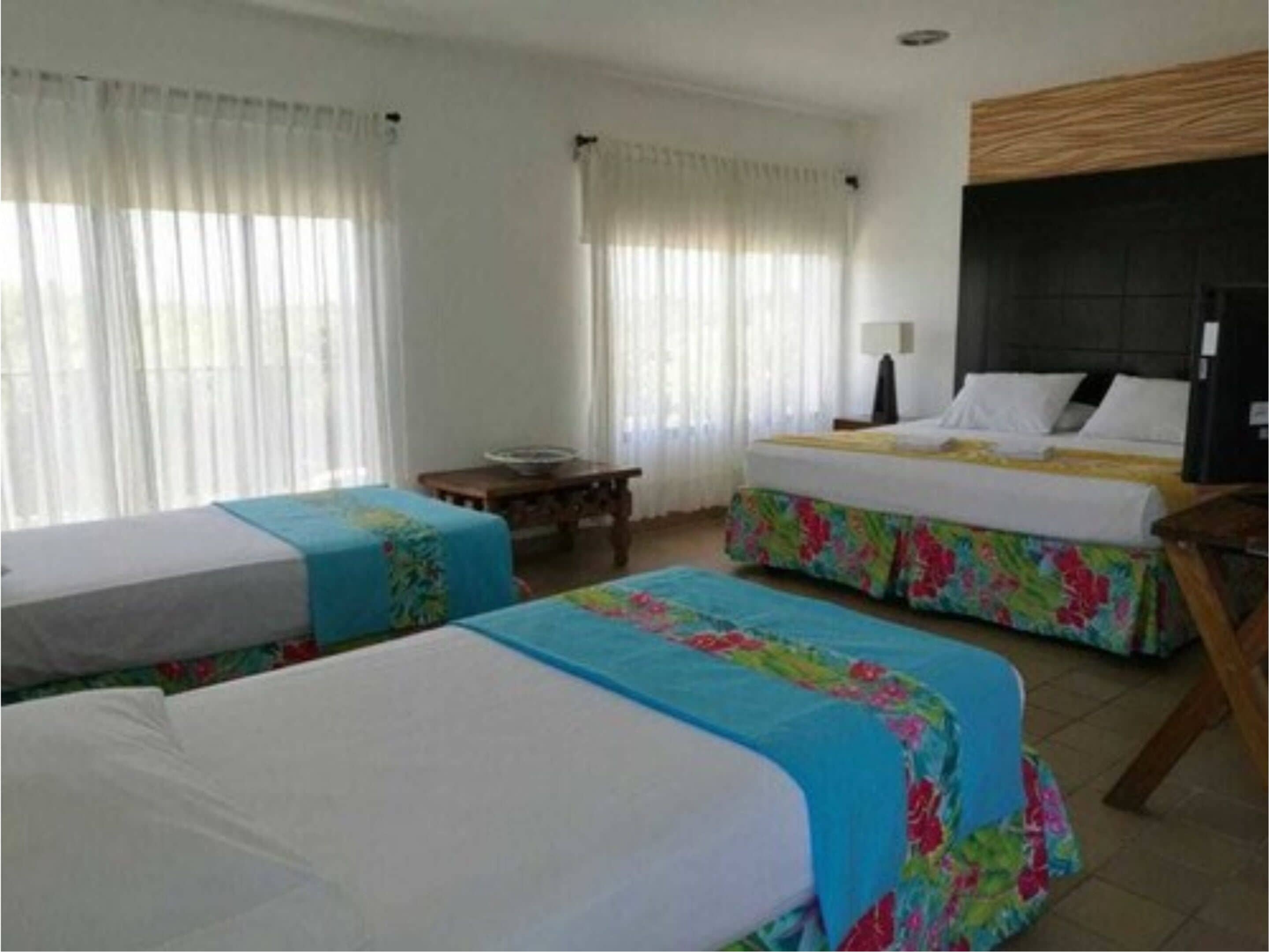 A hotel room with two beds, a desk, a chair, and a TV.
