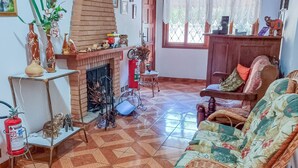 Una sala de estar con chimenea, muebles de mimbre y piso de baldosas.