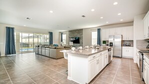 A spacious kitchen with a large island, white cabinets, and a built-in oven. - Windsor at Westside 1749 (Kissimmee)