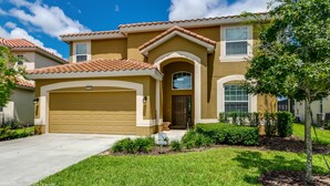 A two-story house with a brown facade, a red-tiled roof, and a garage. - Solterra 5196 (Davenport)