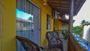 A balcony with wicker chairs, a wooden railing, and a yellow wall. - Villa Nobre Residence (Porto Seguro)