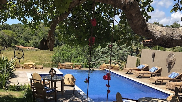 A backyard with a swimming pool, lounge chairs, and a deck area. - Villa Nobre Residence (Porto Seguro)