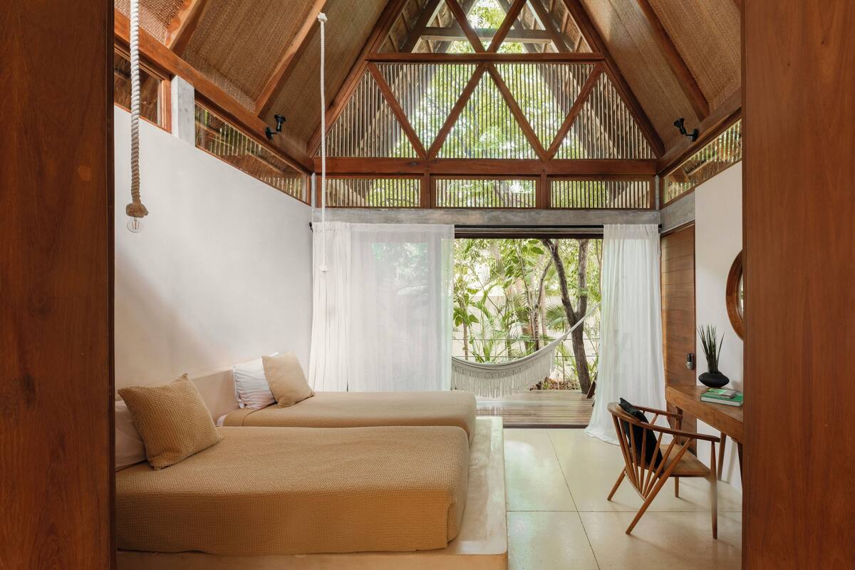 A room with a bed, a desk, and a hammock.