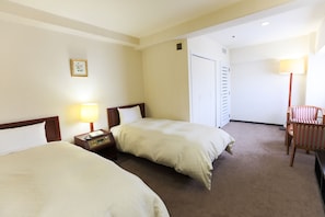 A hotel room with two beds, a desk, a chair, a lamp, and a door. - Hotel New Carina (Morioka)