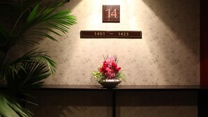 A room with a floral arrangement on a table, a number sign above indicating room 14, and a range sign for rooms 1401-1423. - Hotel New Carina (Morioka)