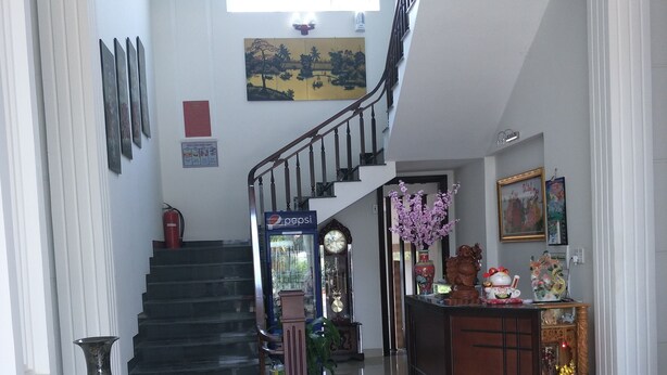 A spacious living area with a staircase, a large vase, and a decorative cabinet. - Hotel Nguyen Ngoc (Cu Jut)