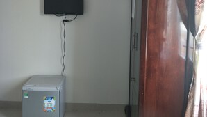 A room with a wooden cabinet, a wall-mounted fan, a television, and a small refrigerator. - Hotel Nguyen Ngoc (Cu Jut)